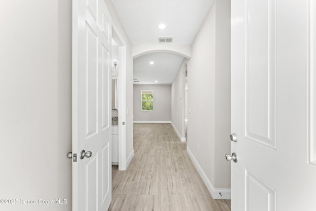 1427 Damon Rd SE, Palm Bay, FL 32909 - hallway with arched walkways, baseboards, recessed lighting, and light wood finished floors