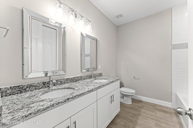 1427 Damon Rd SE, Palm Bay, FL 32909 - bathroom with double vanity, toilet, wood finished floors, baseboards, and washtub / shower combination