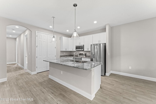 1427 Damon Rd SE, Palm Bay, FL 32909 - kitchen featuring appliances with stainless steel finishes, a sink, arched walkways, baseboards, and an island with sink