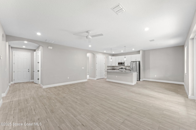 1427 Damon Rd SE, Palm Bay, FL 32909 - unfurnished living room featuring arched walkways, recessed lighting, a ceiling fan, baseboards, and light wood-style floors