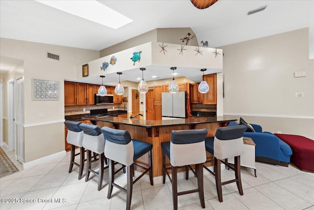 1510 Jupiter Blvd NW, Palm Bay, FL 32907 - kitchen with freestanding refrigerator, stainless steel microwave, lofted ceiling, brown cabinetry, and tasteful backsplash