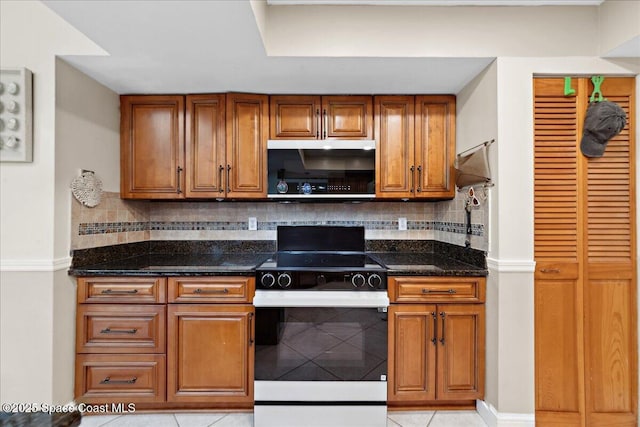 1510 Jupiter Blvd NW, Palm Bay, FL 32907 - kitchen featuring stainless steel microwave, stove, light tile patterned flooring, dark stone countertops, and brown cabinets