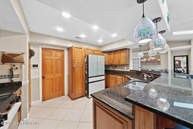1510 Jupiter Blvd NW, Palm Bay, FL 32907 - kitchen with freestanding refrigerator, a sink, hanging light fixtures, brown cabinets, and backsplash