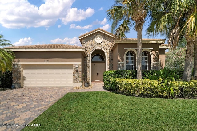 2770 Grand Isle Way SW, Vero Beach, FL 32968 - mediterranean / spanish-style house featuring stucco siding, a garage, decorative driveway, stone siding, and a front yard