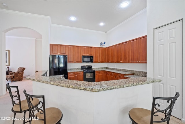 2770 Grand Isle Way SW, Vero Beach, FL 32968 - kitchen featuring black appliances, a kitchen breakfast bar, arched walkways, ornamental molding, and brown cabinets