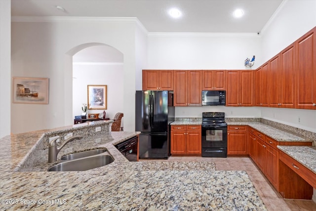 2770 Grand Isle Way SW, Vero Beach, FL 32968 - kitchen featuring black appliances, arched walkways, ornamental molding, light stone counters, and brown cabinets