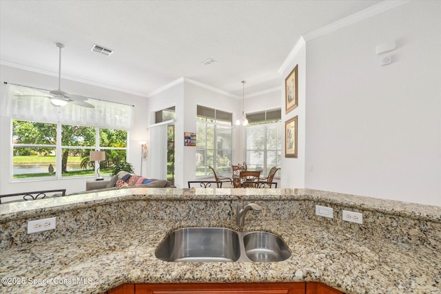 2770 Grand Isle Way SW, Vero Beach, FL 32968 - kitchen with ornamental molding, light stone countertops, a ceiling fan, and pendant lighting
