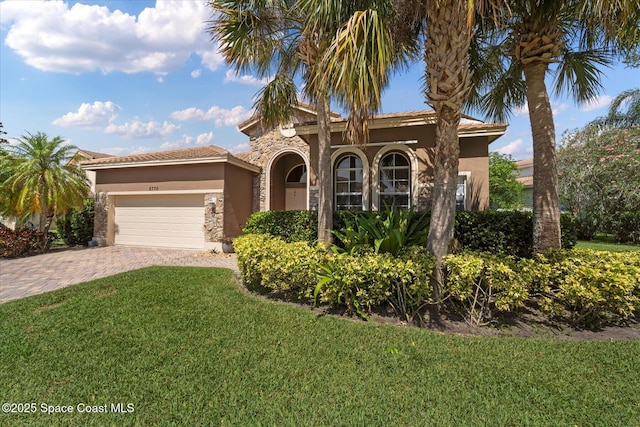 2770 Grand Isle Way SW, Vero Beach, FL 32968 - mediterranean / spanish home with stucco siding, stone siding, an attached garage, a front lawn, and decorative driveway