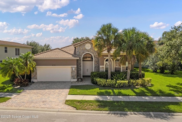 2770 Grand Isle Way SW, Vero Beach, FL 32968 - mediterranean / spanish home with stone siding, a garage, a front yard, stucco siding, and driveway