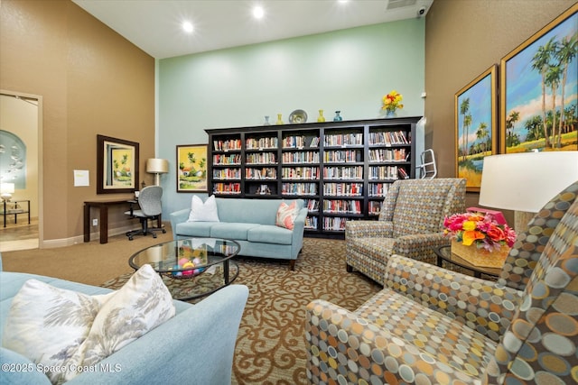 2770 Grand Isle Way SW, Vero Beach, FL 32968 - living room featuring carpet flooring, a towering ceiling, recessed lighting, and bookshelves