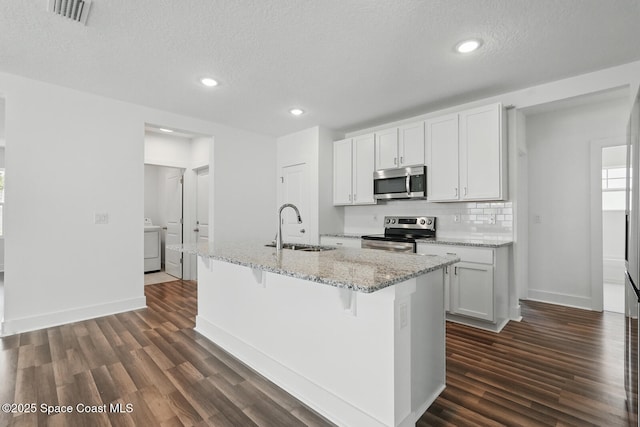 15 Ponderosa Ln, Palm Coast, FL 32164 - kitchen with appliances with stainless steel finishes, a sink, a center island with sink, dark wood-type flooring, and baseboards