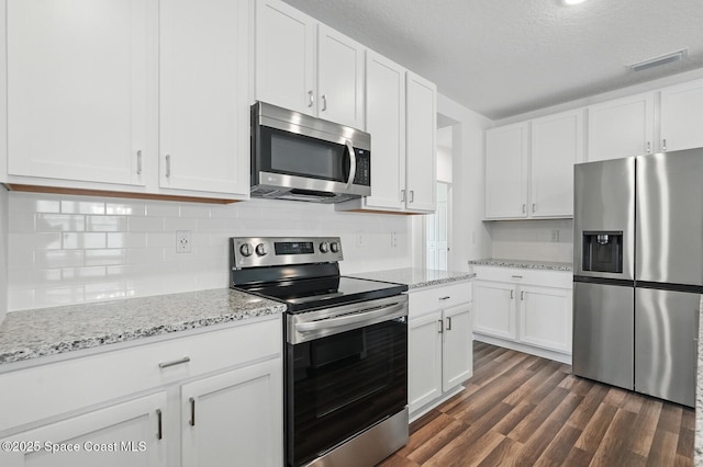 15 Ponderosa Ln, Palm Coast, FL 32164 - kitchen featuring appliances with stainless steel finishes, white cabinets, dark wood finished floors, tasteful backsplash, and a textured ceiling