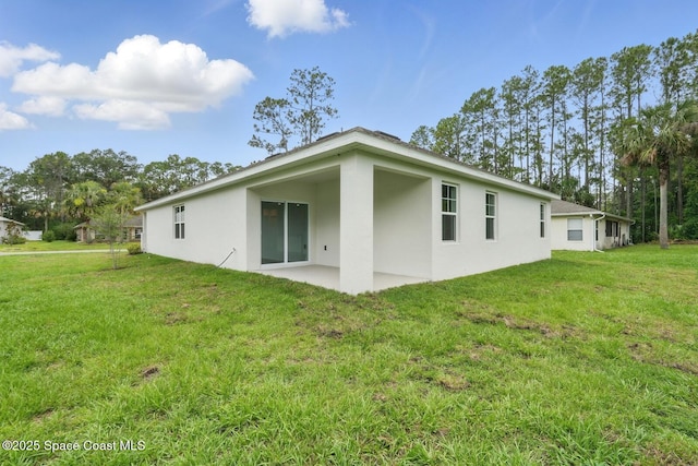 15 Ponderosa Ln, Palm Coast, FL 32164 - back of house with stucco siding, a patio area, and a lawn