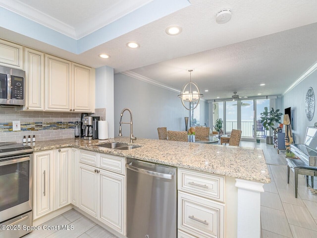 2815 S Atlantic Ave Unit 705, Cocoa Beach, FL 32931 - kitchen with stainless steel appliances, a sink, ornamental molding, cream cabinetry, and a peninsula