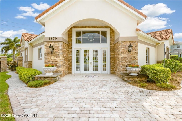 1475 Isabella Dr Unit 101, Melbourne, FL 32935 - doorway to property featuring french doors, a tile roof, stone siding, and stucco siding