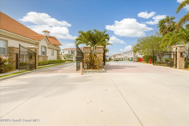 1475 Isabella Dr Unit 101, Melbourne, FL 32935 - view of concrete road featuring a residential view, curbs, a gate, and a gated entry