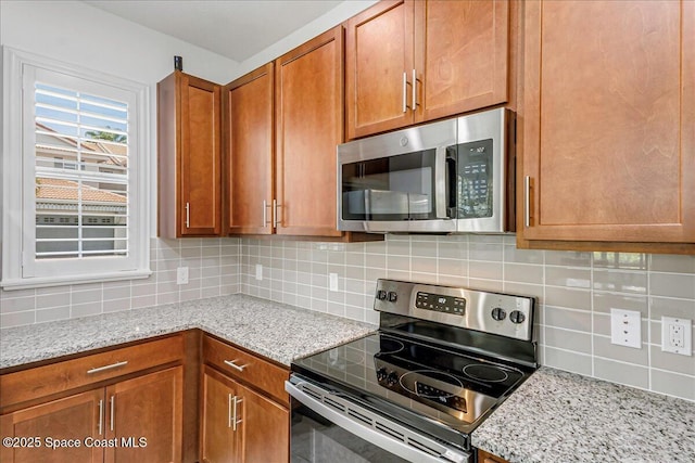 1475 Isabella Dr Unit 101, Melbourne, FL 32935 - kitchen featuring stainless steel appliances, decorative backsplash, brown cabinets, and light stone countertops