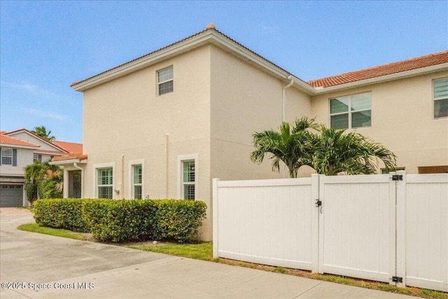 1475 Isabella Dr Unit 101, Melbourne, FL 32935 - view of home's exterior with stucco siding, a gate, and a tiled roof