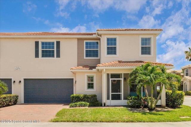 1475 Isabella Dr Unit 101, Melbourne, FL 32935 - view of front of house featuring a tiled roof, a garage, driveway, and stucco siding