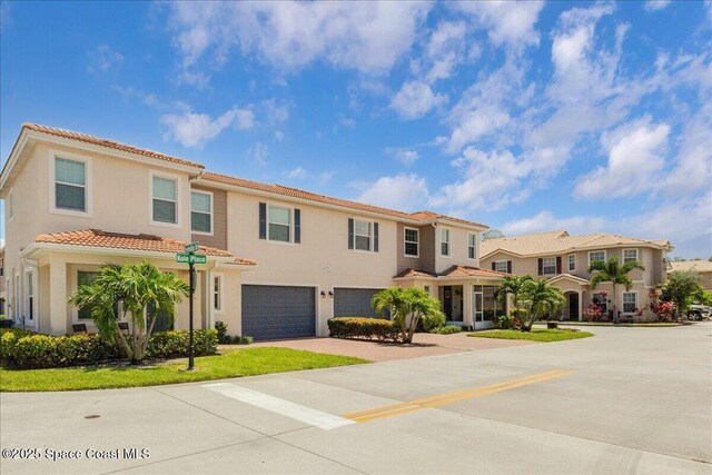 1475 Isabella Dr Unit 101, Melbourne, FL 32935 - view of front facade featuring an attached garage, concrete driveway, a tile roof, stucco siding, and a residential view