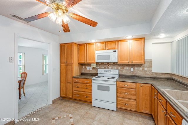 957 Waialae Cir NE, Palm Bay, FL 32905 - kitchen with white appliances, light tile patterned flooring, dark countertops, ceiling fan, and tasteful backsplash