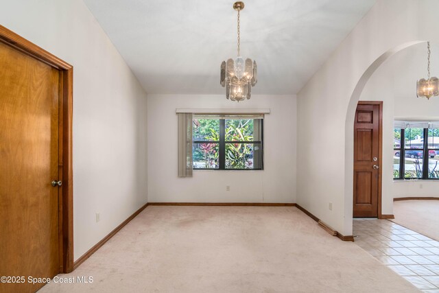1262 Heberling St NW, Palm Bay, FL 32907 - empty room featuring a chandelier, arched walkways, light colored carpet, and baseboards
