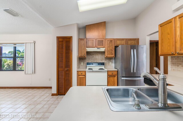 1262 Heberling St NW, Palm Bay, FL 32907 - kitchen featuring white range with electric stovetop, freestanding refrigerator, a sink, under cabinet range hood, and tasteful backsplash