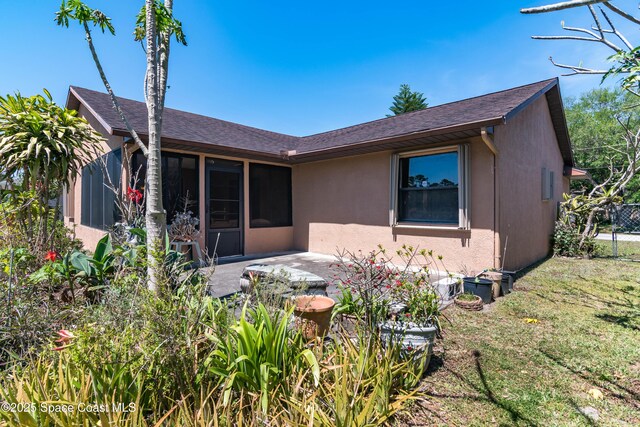 1262 Heberling St NW, Palm Bay, FL 32907 - view of front facade with stucco siding, a patio area, a front yard, a sunroom, and a shingled roof