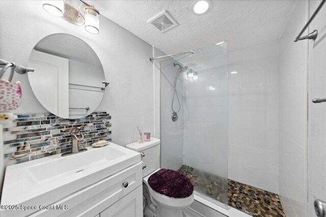 221 Columbia Dr Unit 139, Cape Canaveral, FL 32920 - bathroom featuring toilet, decorative backsplash, vanity, tiled shower, and a textured ceiling