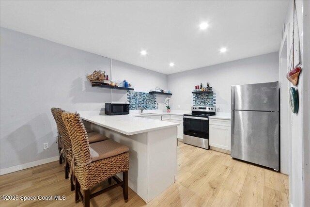 221 Columbia Dr Unit 139, Cape Canaveral, FL 32920 - kitchen with appliances with stainless steel finishes, open shelves, a peninsula, white cabinets, and light wood-style flooring