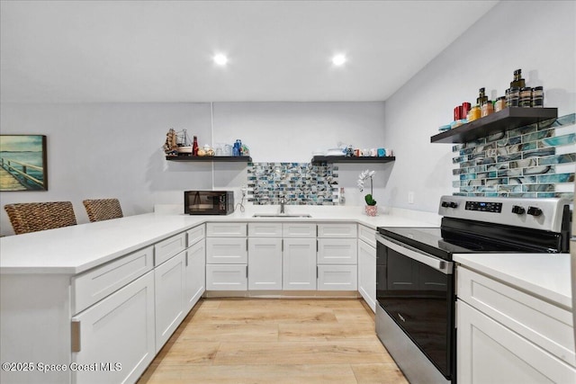 221 Columbia Dr Unit 139, Cape Canaveral, FL 32920 - kitchen with open shelves, electric range, a sink, a peninsula, and light wood-style floors