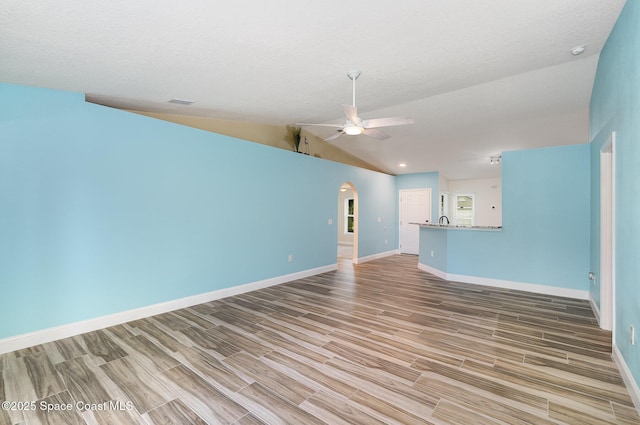 2111 Spring Creek Cir, Palm Bay, FL 32905 - unfurnished living room featuring a ceiling fan, baseboards, arched walkways, wood finished floors, and vaulted ceiling