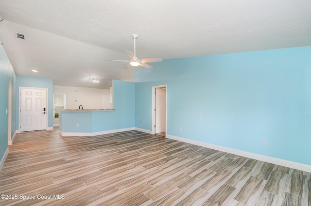 2111 Spring Creek Cir, Palm Bay, FL 32905 - unfurnished living room with light wood-type flooring, baseboards, a ceiling fan, a textured ceiling, and lofted ceiling