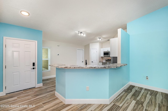 2111 Spring Creek Cir, Palm Bay, FL 32905 - kitchen with stainless steel appliances, light wood-style floors, baseboards, light stone counters, and a textured ceiling