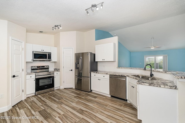 2111 Spring Creek Cir, Palm Bay, FL 32905 - kitchen featuring appliances with stainless steel finishes, a peninsula, a sink, tasteful backsplash, and white cabinets