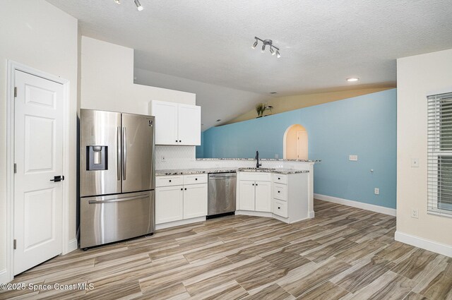 2111 Spring Creek Cir, Palm Bay, FL 32905 - kitchen featuring appliances with stainless steel finishes, a peninsula, a sink, white cabinets, and baseboards