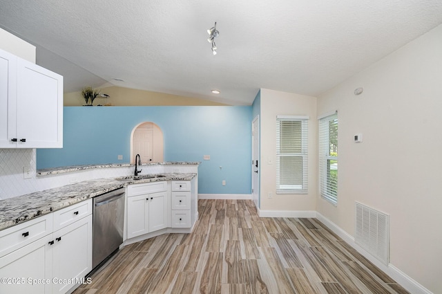 2111 Spring Creek Cir, Palm Bay, FL 32905 - kitchen featuring dishwasher, lofted ceiling, a sink, a peninsula, and white cabinetry