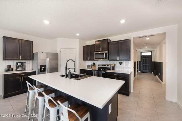 4791 Talbot Blvd, Cocoa, FL 32926 - kitchen featuring appliances with stainless steel finishes, decorative backsplash, light tile patterned floors, a breakfast bar, and light countertops