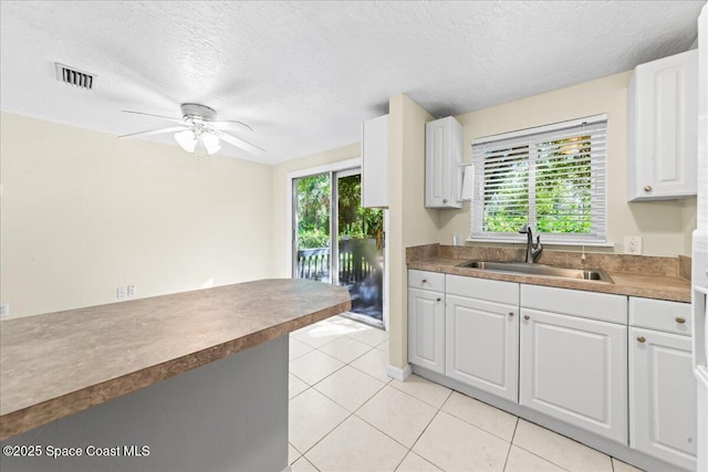 501 Santo Domingo Ave SW, Palm Bay, FL 32908 - kitchen featuring healthy amount of natural light, a textured ceiling, white cabinets, a ceiling fan, and light tile patterned floors