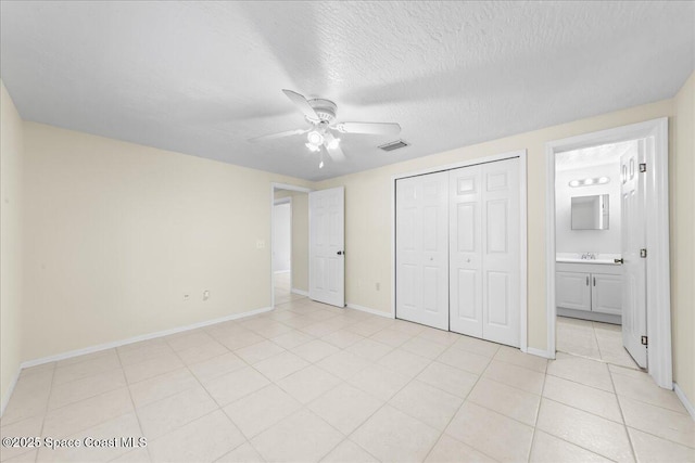 501 Santo Domingo Ave SW, Palm Bay, FL 32908 - unfurnished bedroom with light tile patterned floors, a closet, ceiling fan, a textured ceiling, and ensuite bathroom