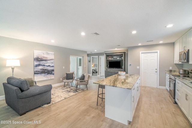 1237 Glenham Dr NE, Palm Bay, FL 32905 - kitchen featuring stainless steel appliances, open floor plan, a kitchen island, a kitchen bar, and white cabinets