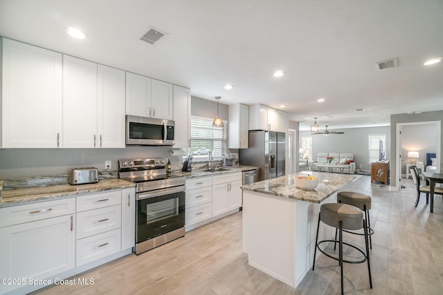 1237 Glenham Dr NE, Palm Bay, FL 32905 - kitchen featuring appliances with stainless steel finishes, a sink, open floor plan, white cabinetry, and plenty of natural light