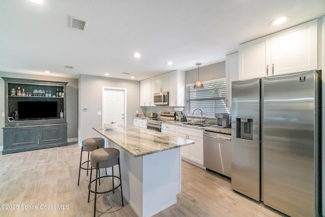 1237 Glenham Dr NE, Palm Bay, FL 32905 - kitchen featuring stainless steel appliances, a sink, a kitchen bar, white cabinets, and recessed lighting