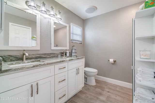 1237 Glenham Dr NE, Palm Bay, FL 32905 - bathroom featuring double vanity, toilet, wood finished floors, and baseboards