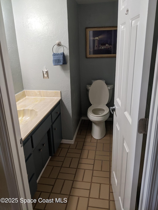 199 Skyline Ct, Satellite Beach, FL 32937 - bathroom with vanity, toilet, baseboards, and brick patterned flooring