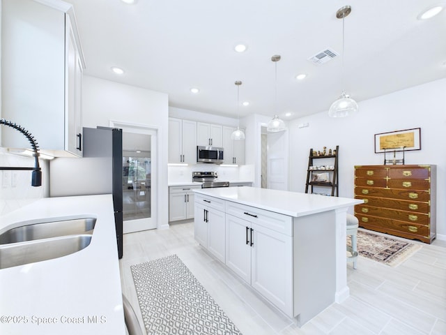 3466 Rixford Way, Palm Bay, FL 32909 - kitchen with appliances with stainless steel finishes, a sink, light countertops, white cabinets, and a center island