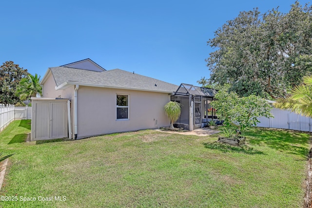 310 Chennault Ln, Rockledge, FL 32955 - rear view of property with a fenced backyard, stucco siding, a sunroom, a storage unit, and a shingled roof