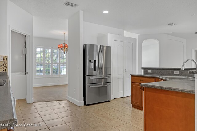 310 Chennault Ln, Rockledge, FL 32955 - kitchen with stainless steel fridge with ice dispenser, dark countertops, a chandelier, light tile patterned floors, and recessed lighting