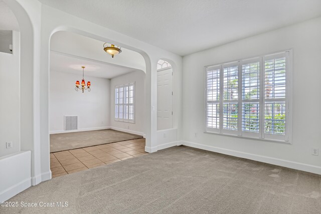 310 Chennault Ln, Rockledge, FL 32955 - tiled spare room with carpet flooring, a chandelier, and arched walkways