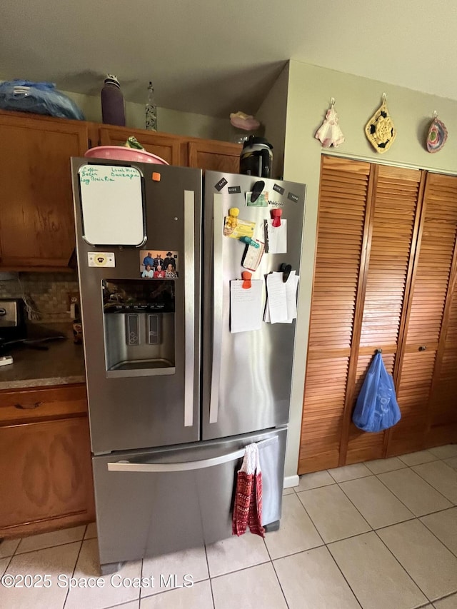 237 Jacaranda Ave NW, Palm Bay, FL 32907 - kitchen with stainless steel fridge, light tile patterned flooring, brown cabinetry, and backsplash